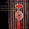 Ten copper coins and a plum blossom fortune amulet pendant with a Chinese knot hanging from bamboo rods.