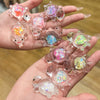 A hand holds several glow-in-the-dark mini sea turtle figurines with colorful glitter for DIY crafts.