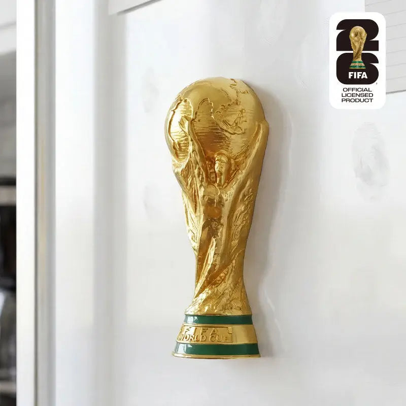 A gold FIFA 2026 World Cup trophy fridge magnet displayed on a white surface.