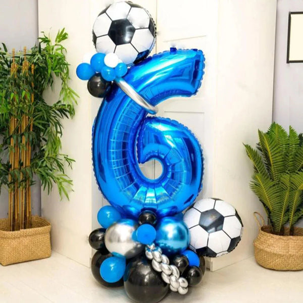 A large blue foil balloon shaped like the number 6 is displayed with various black and blue balloons.