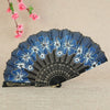 A dark blue and black antique folding fan decorated with white and blue floral patterns.