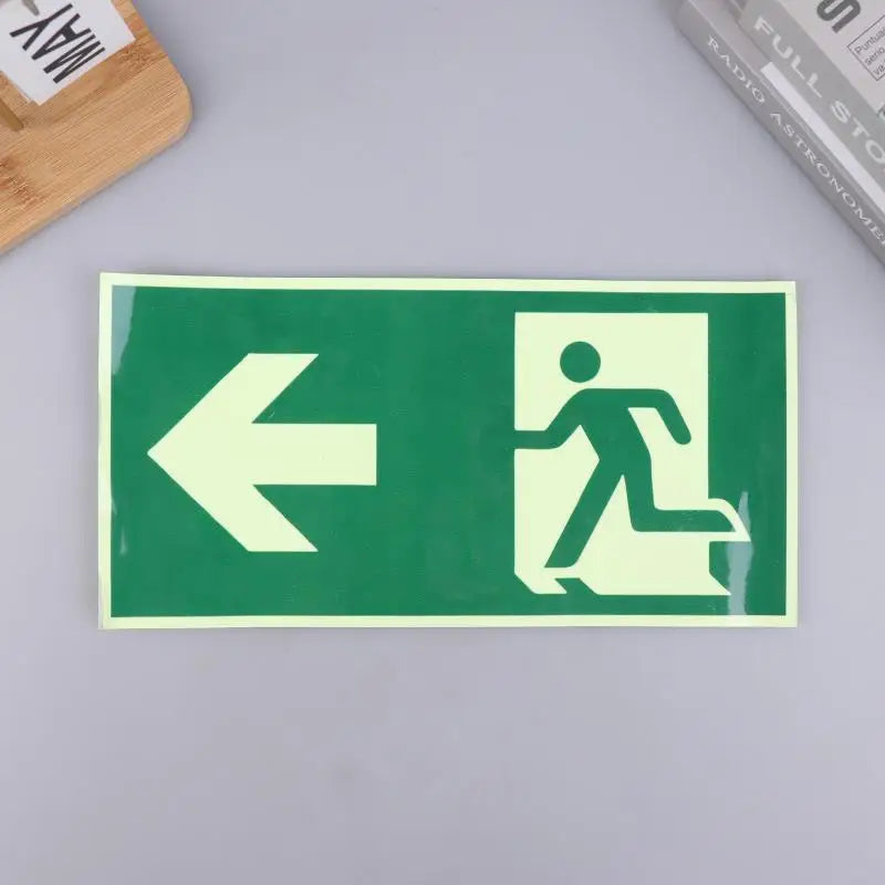 A rectangular green photoluminescent emergency exit sign decal with a white arrow pointing left and a silhouette of a person 