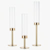 A set of three tall, cylindrical hurricane candle holders with gold and silver finishes.