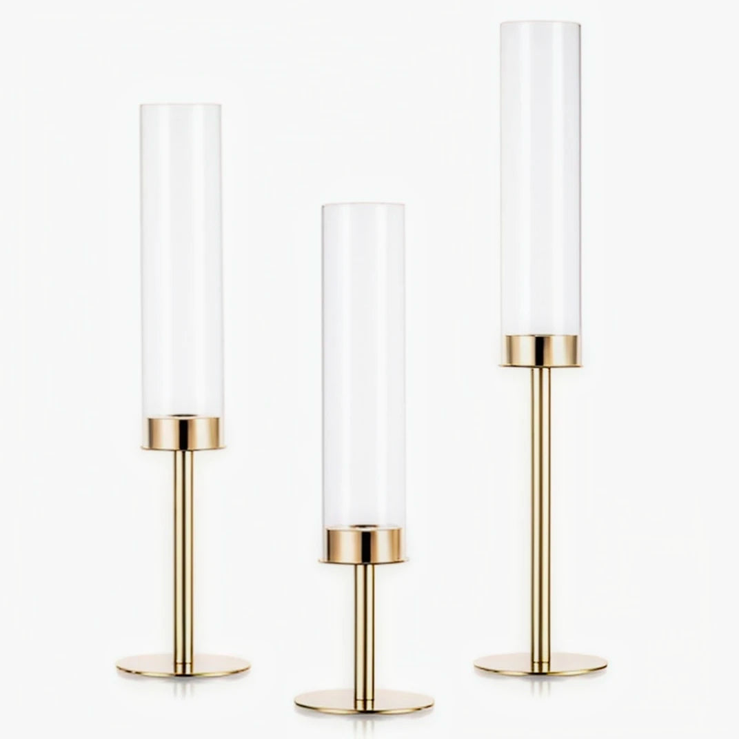 A set of three tall, cylindrical hurricane candle holders with gold and silver finishes.