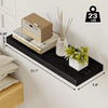A black floating wall shelf displaying a potted plant and some dried sticks, mounted on a white wall.