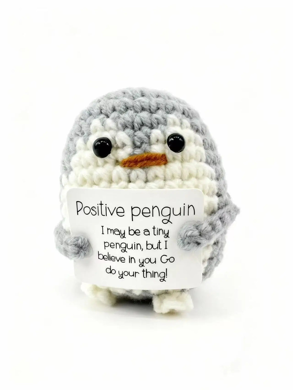A handmade crochet penguin doll with a positivity card attached.