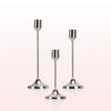 A set of modern metal taper candle holders with slender stems and flared bases.