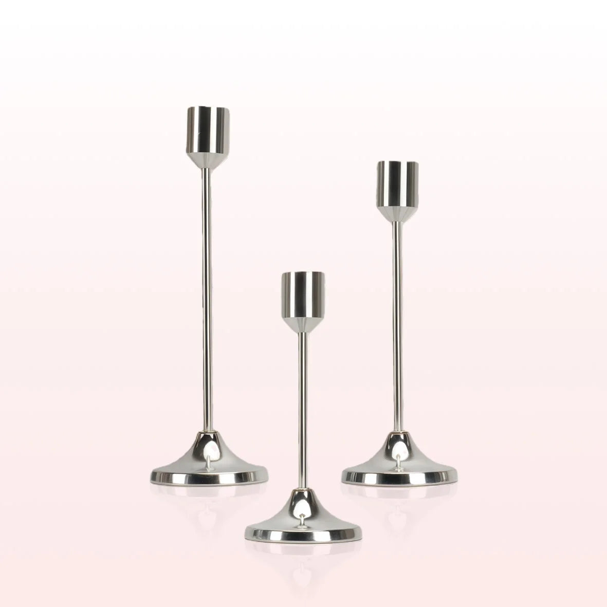 A set of modern metal taper candle holders with slender stems and flared bases.