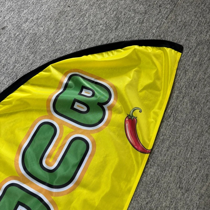 Yellow feather flag advertising banner with green lettering and a red chili pepper illustration.