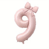 A large pink foil number balloon shaped like the number 9 with a bow.