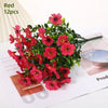 A bundle of red artificial daisy flowers with green leaves displayed on a white background.