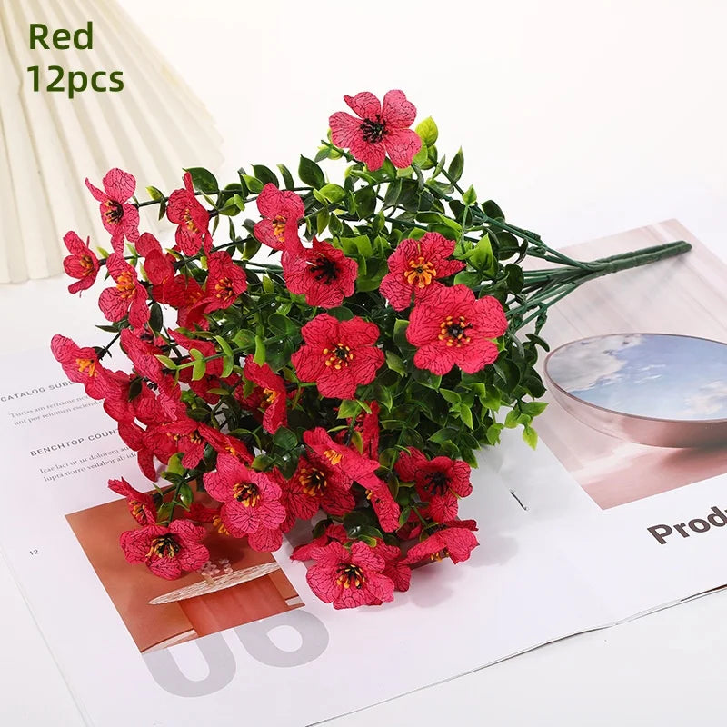 A bundle of red artificial daisy flowers with green leaves displayed on a white background.