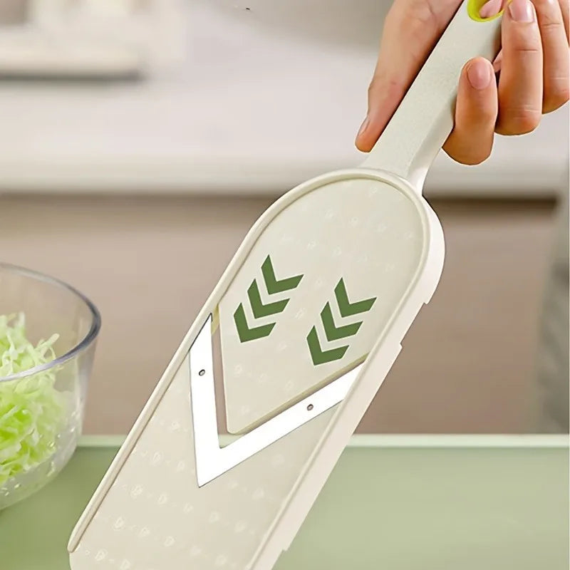 A hand holds a manual cabbage shredder with stainless steel blades, showing the green cutting lines.