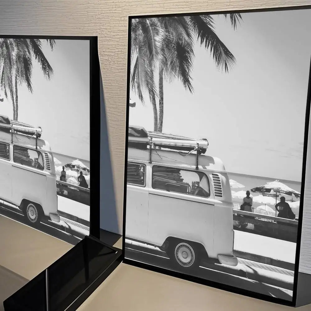Black and white photograph of a vintage van parked near a beach with palm trees.