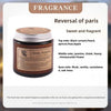 A jar of Reverse of Paris scented candle with a gold lid and label detailing the fragrance notes.