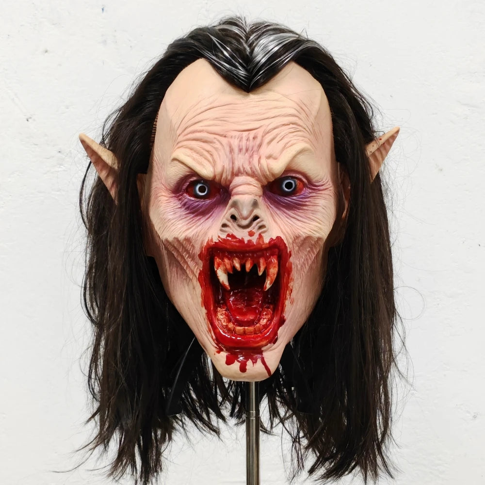 Lifelike vampire mask of a woman with pale skin, long dark hair, and bloody fangs.