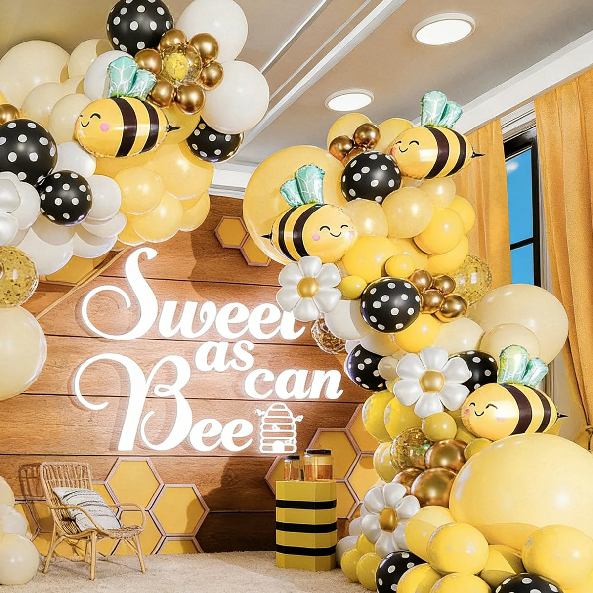 A yellow and black bee balloon garland decoration setup with balloons and a wooden background.