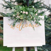 A sign with the words welcome decorated with green eucalyptus leaves and pink roses for home decor
