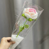 A handmade crochet tulip bouquet featuring pink and white flowers with green stems, displayed in clear plastic packaging.