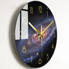 A round wall clock face with a black background and gold hour markers, featuring a galaxy design and a vertical window displa