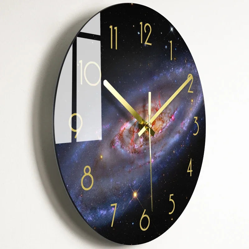 A round wall clock face with a black background and gold hour markers, featuring a galaxy design and a vertical window displa