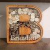 Alphabet wooden piggy bank coin box shaped like the letter B with coins inside