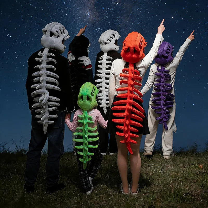 Un groupe de personnes posant avec des peluches squelettes de dinosaures sur fond de ciel nocturne.