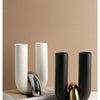 A set of three U-shaped ceramic tabletop vases in white and black, with a gold accent piece.