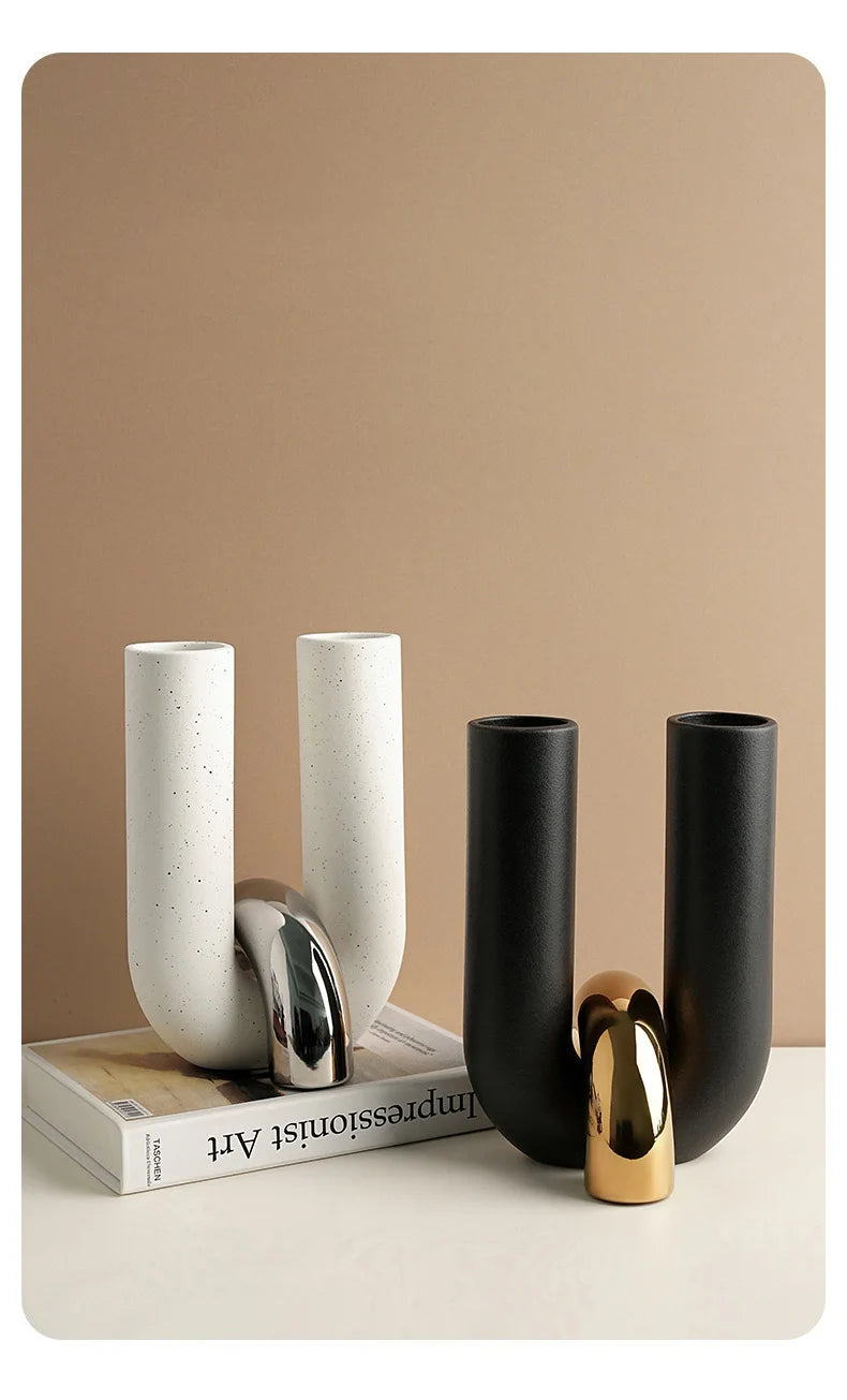 A set of three U-shaped ceramic tabletop vases in white and black, with a gold accent piece.