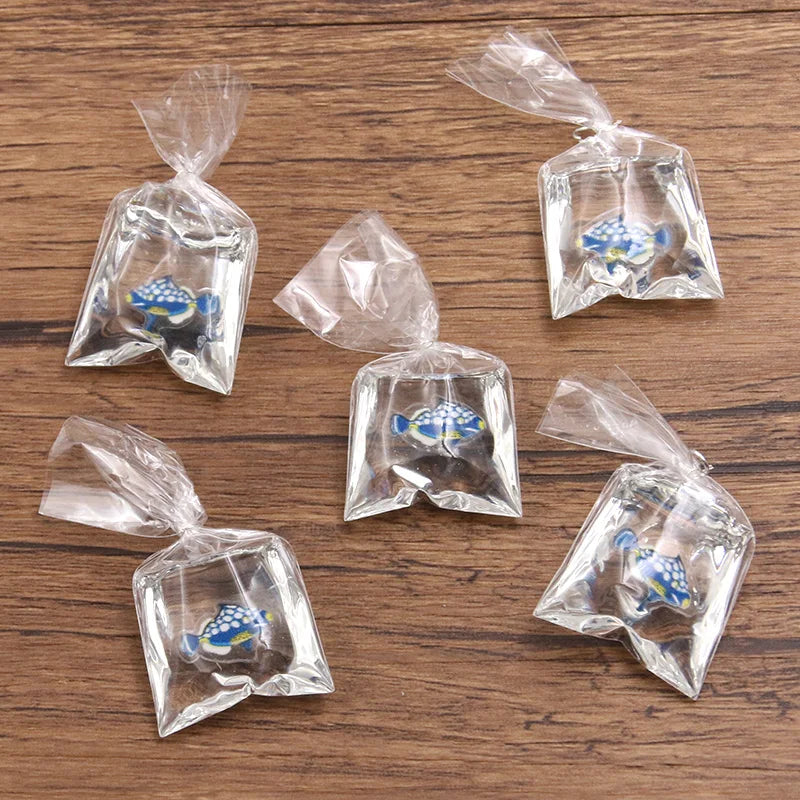 Un set de adornos de pez payaso de resina transparente, empaquetados en pequeñas bolsas de plástico para hacer joyería
