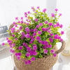 A vibrant faux plant featuring numerous purple flowers on green foliage, potted in a woven basket.