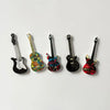 A set of five guitar-shaped fridge magnets in various colors and finishes.