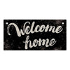A rustic wooden hanging sign with the text Welcome home written in white script on a black distressed background.