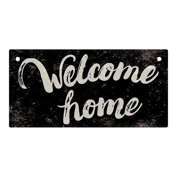 A rustic wooden hanging sign with the text Welcome home written in white script on a black distressed background.