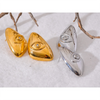 Pair of geometric stud earrings featuring a gold-toned eye design and a silver-toned eye design