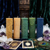 A collection of teal and yellow silicone candle molds displayed on a dark velvet cloth with crystals and gold accents.