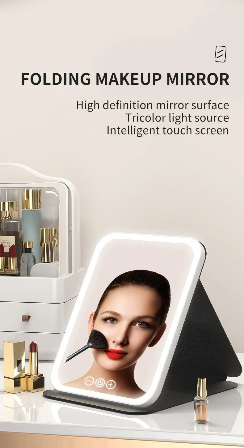 Miroir de maquillage pliable avec écran numérique montrant le visage d'une femme et un pinceau sur une surface blanche.