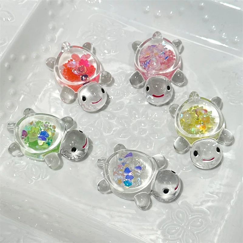 A collection of glow-in-the-dark mini sea turtle figurines with various colorful glitter fillings in a clear mold.