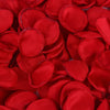 A close-up of vibrant red silk rose petals scattered for weddings and events.