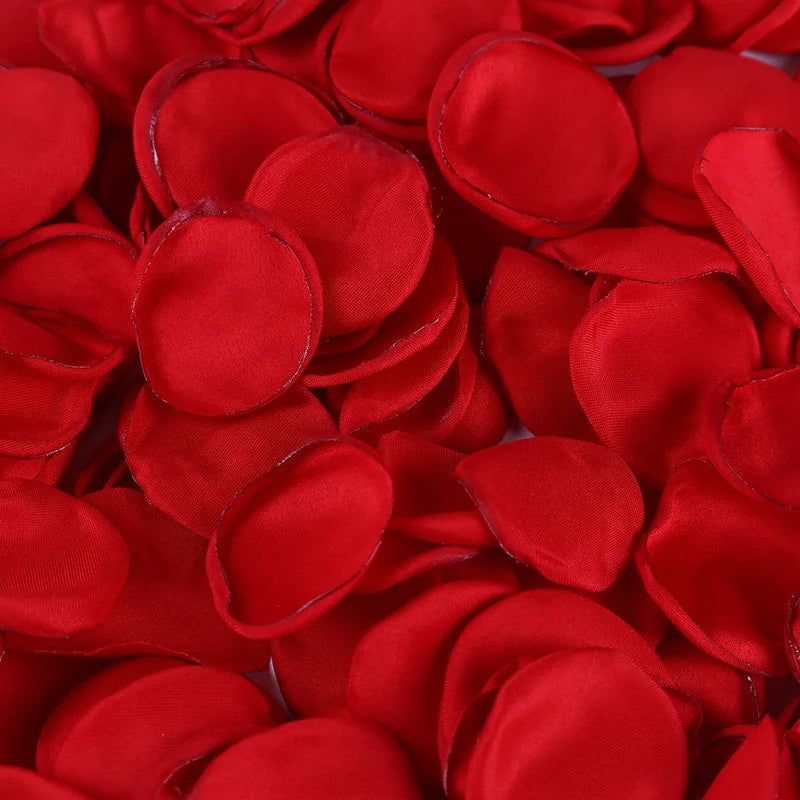 A close-up of vibrant red silk rose petals scattered for weddings and events.