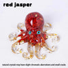 A red jasper octopus statue with clear glass tentacles and blue eyes.