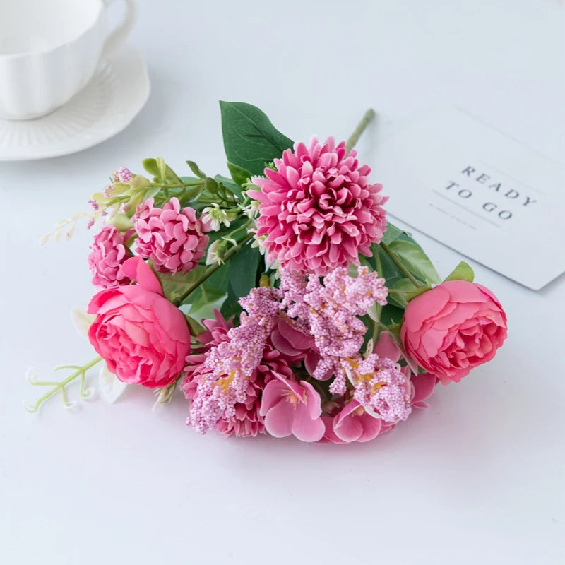 A bouquet of pink and purple artificial silk peony flowers arranged on a white surface.