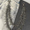 A silver and black spiked chain keychain is displayed against a background of light wash denim jeans.