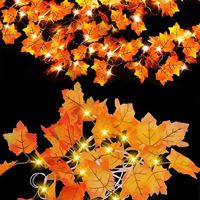 An autumn leaf garland with orange and yellow leaves illuminated by warm LED lights against a black background.