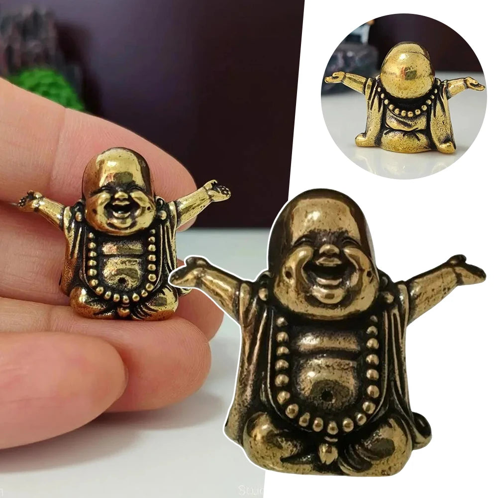 A brass laughing Buddha statue is held in a hand, showing its detailed features and golden color.