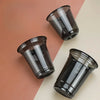 Three disposable black U-shaped coffee cups are arranged on a light background.