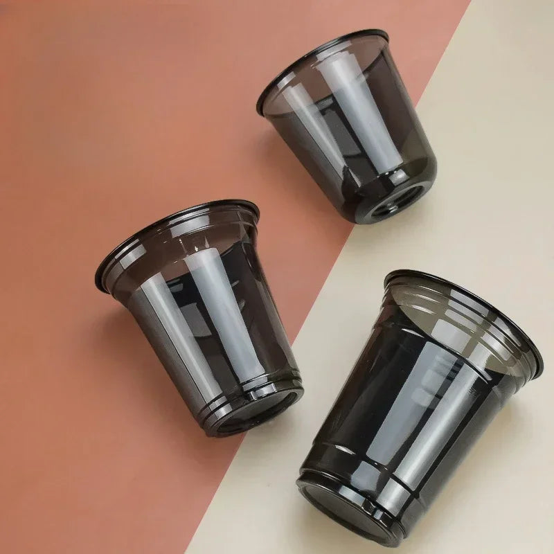 Three disposable black U-shaped coffee cups are arranged on a light background.