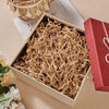 A wooden box filled with crinkle cut paper shred filler next to a red gift box.