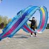 Un hombre realizando una danza de dragón con un gran adorno de tela colorido en forma de dragón, con escamas azules y moradas