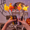 Une main tient une lanterne d'Halloween orange et jaune lumineuse avec un motif de citrouille taillée sur un arrière-plan flo